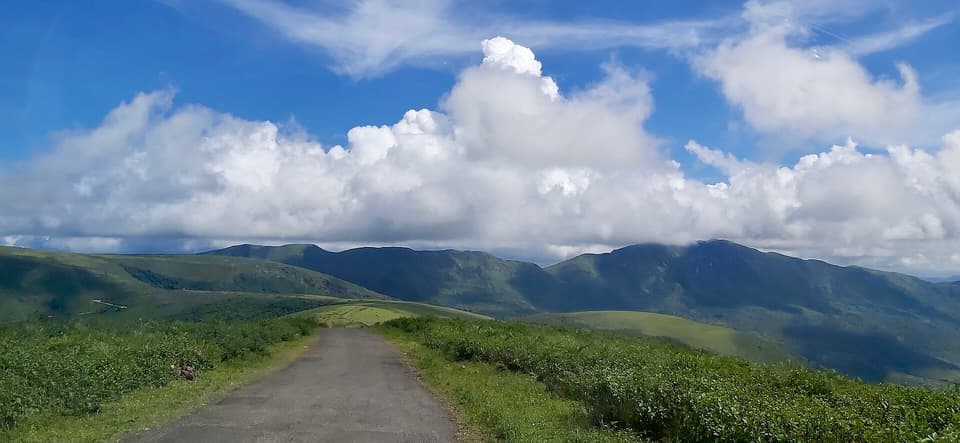Grassy ridge of Deomali with a road running along it under a cloudy sky